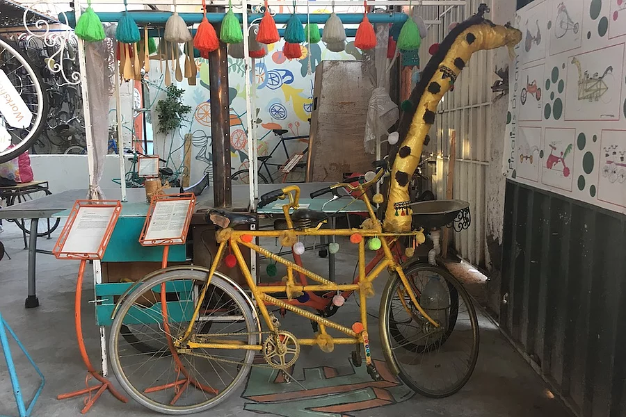 L'image montre une installation artistique saisissante en forme de girafe, située dans les locaux de l'initiative de vélos solidaires Pikala Bikes, au Maroc.